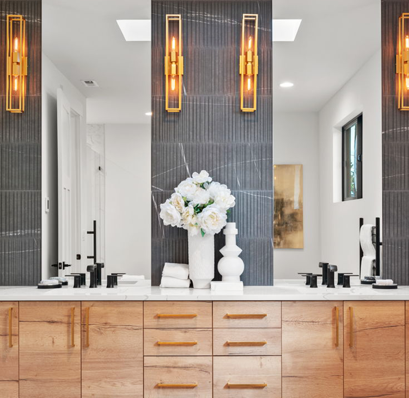A bathroom with two sinks , two mirrors and a vase of flowers on the counter.