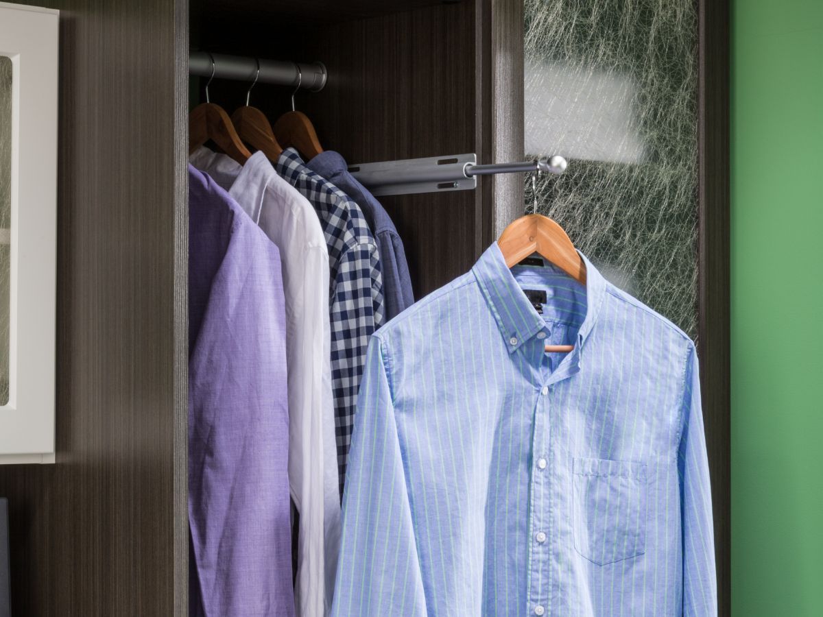 A blue shirt is hanging in a closet with other shirts.