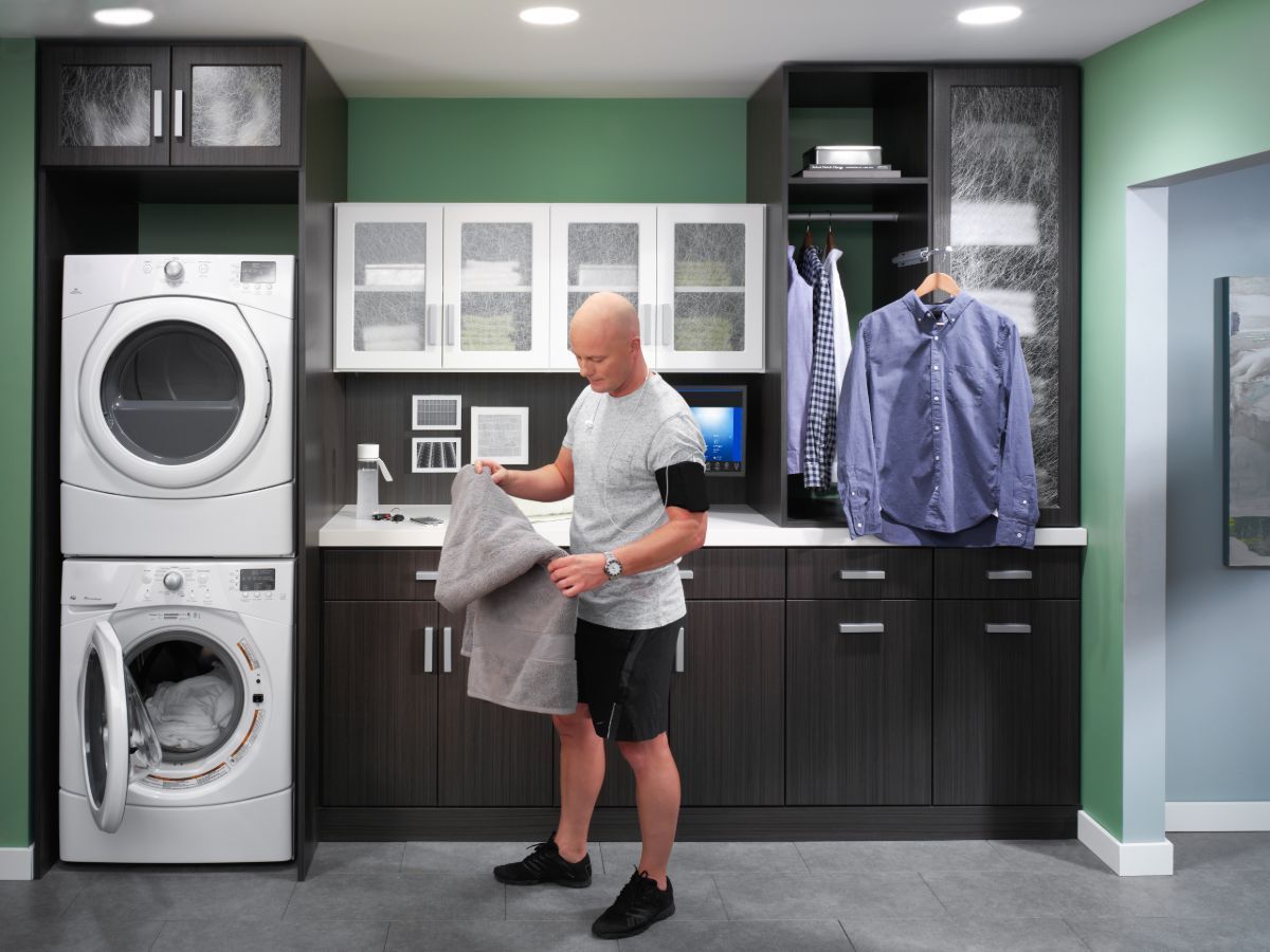 A man is standing in a laundry room next to a washer and dryer.