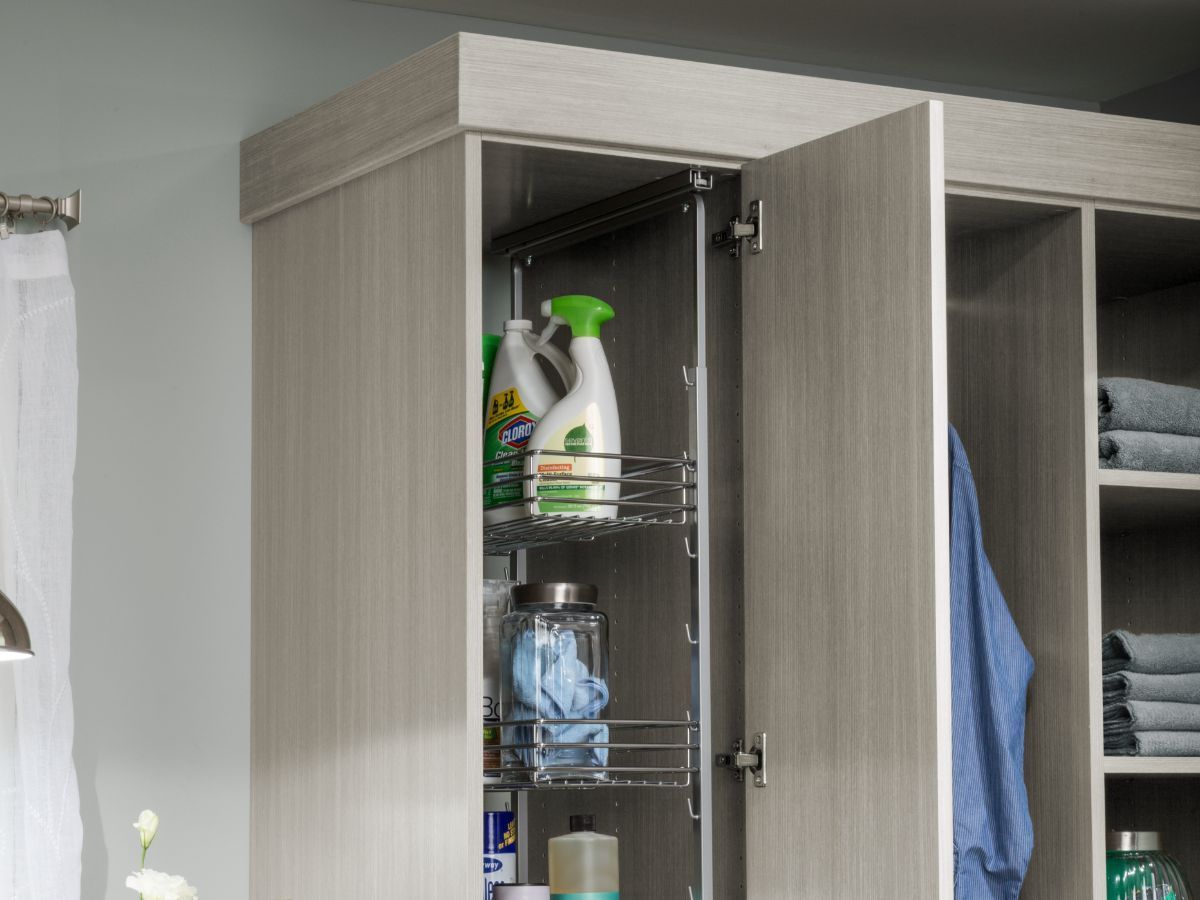 A laundry room cabinet with the door open filled with cleaning supplies