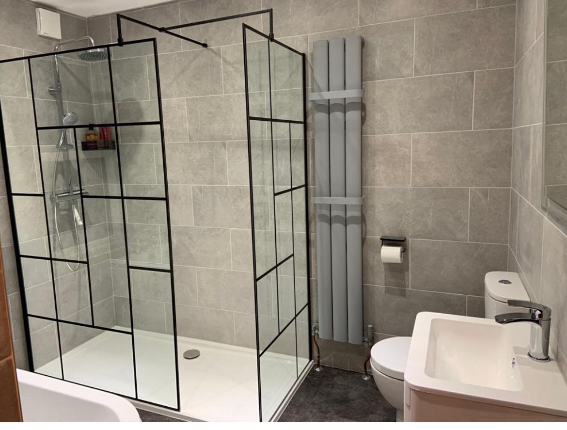 A bathroom with a walk in shower , sink , toilet and mirror.