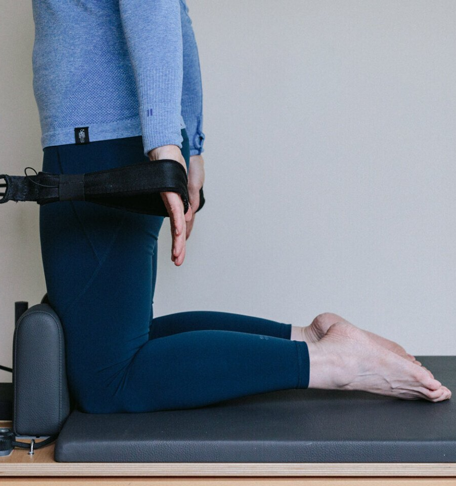 A person is kneeling down on a pilates machine.