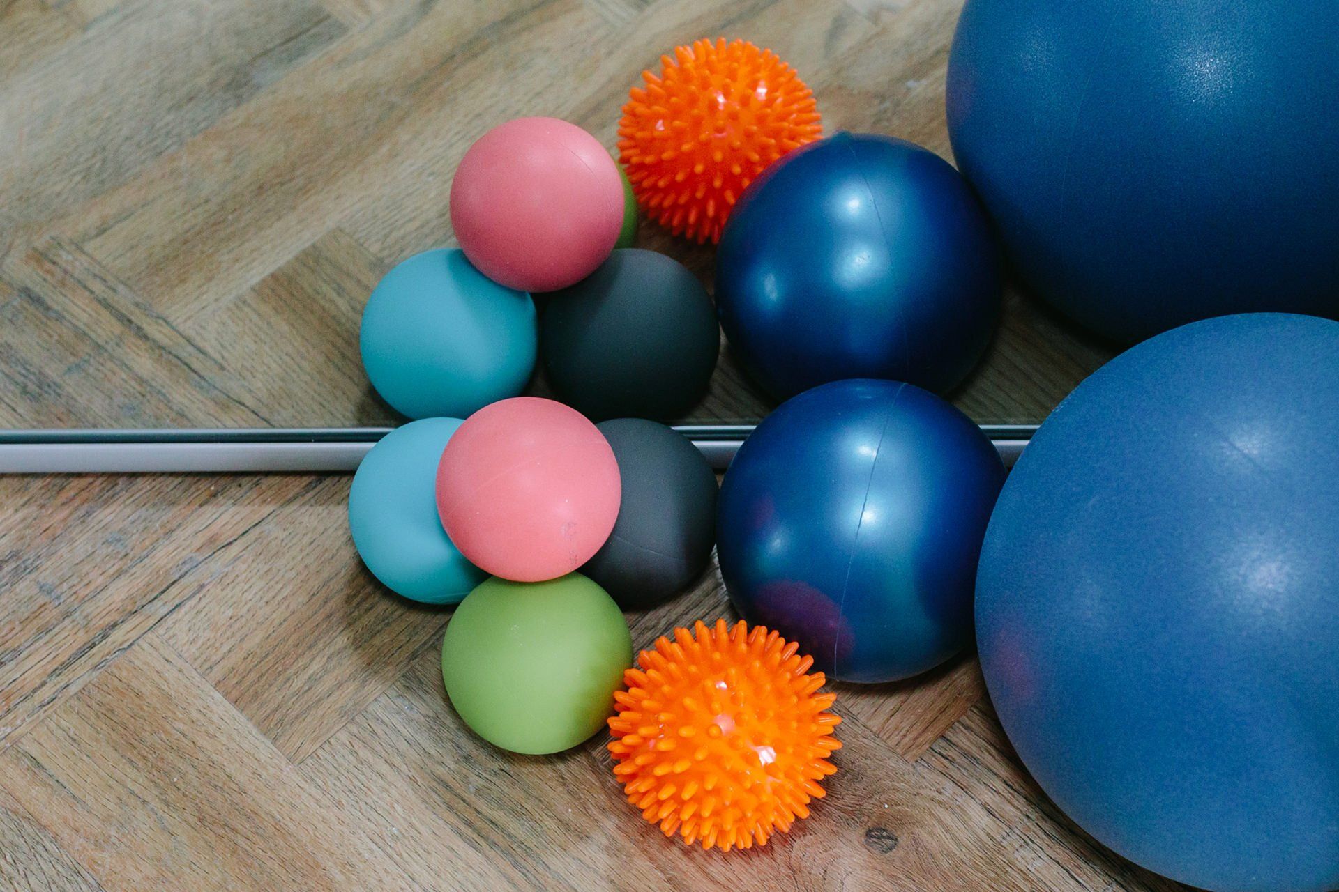 A bunch of balls are stacked on top of each other on a wooden floor.