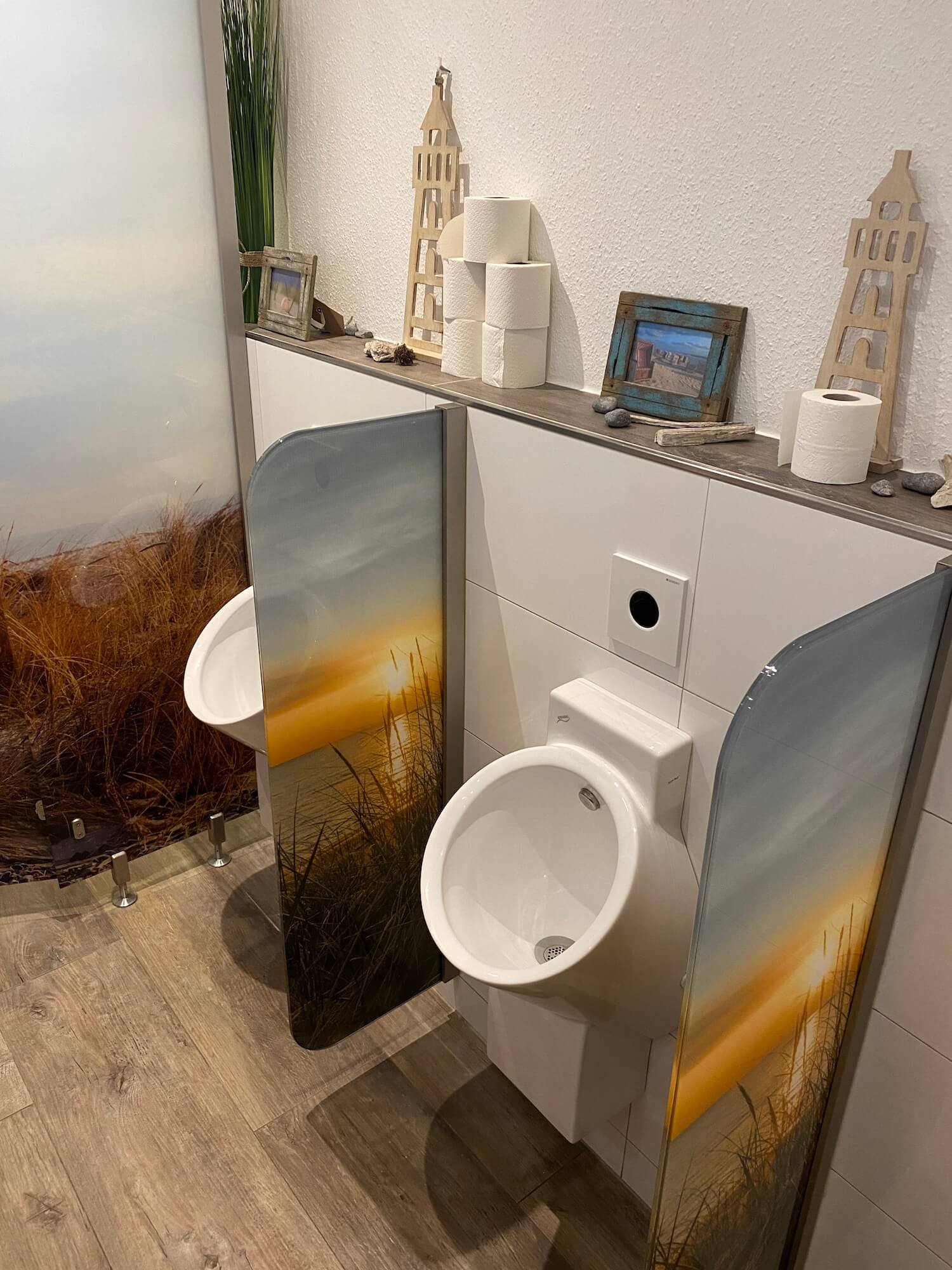 Ein Badezimmer mit zwei Urinalen und Toilettenpapier an der Wand.
