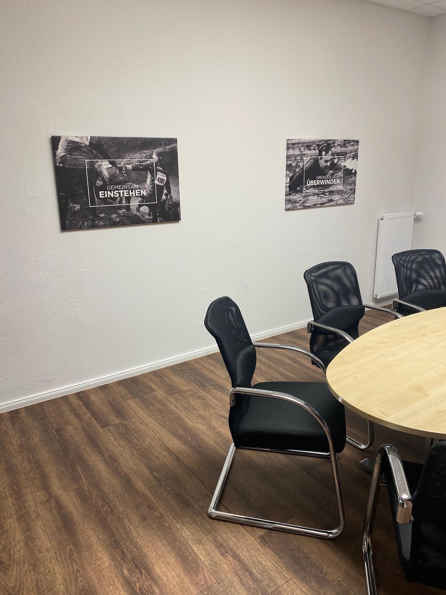 Ein Konferenzraum mit einem Tisch und Stühlen und einem Gemälde an der Wand.