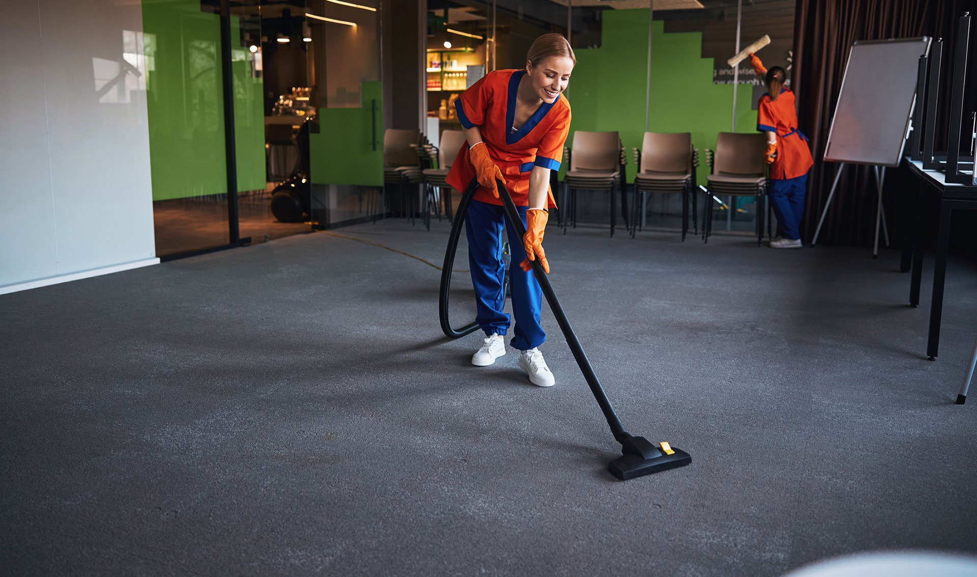 cleaner vacuuming carpet in office conference room