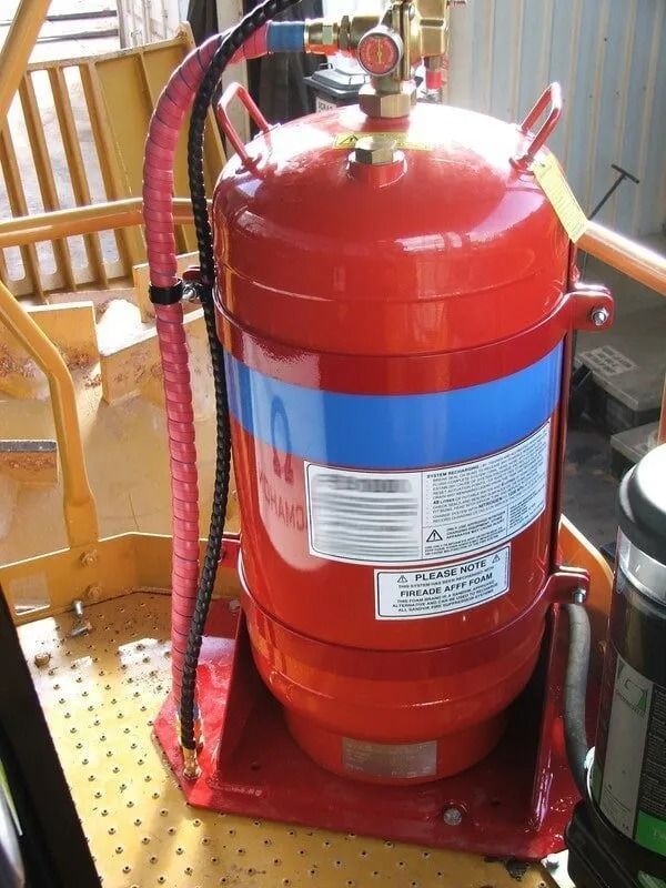 Red and blue cylindrical fire extinguisher with gauge and hose, mounted on a yellow platform. — Fire Maintenance Services (NT) Pty Ltd in Winnellie, NT