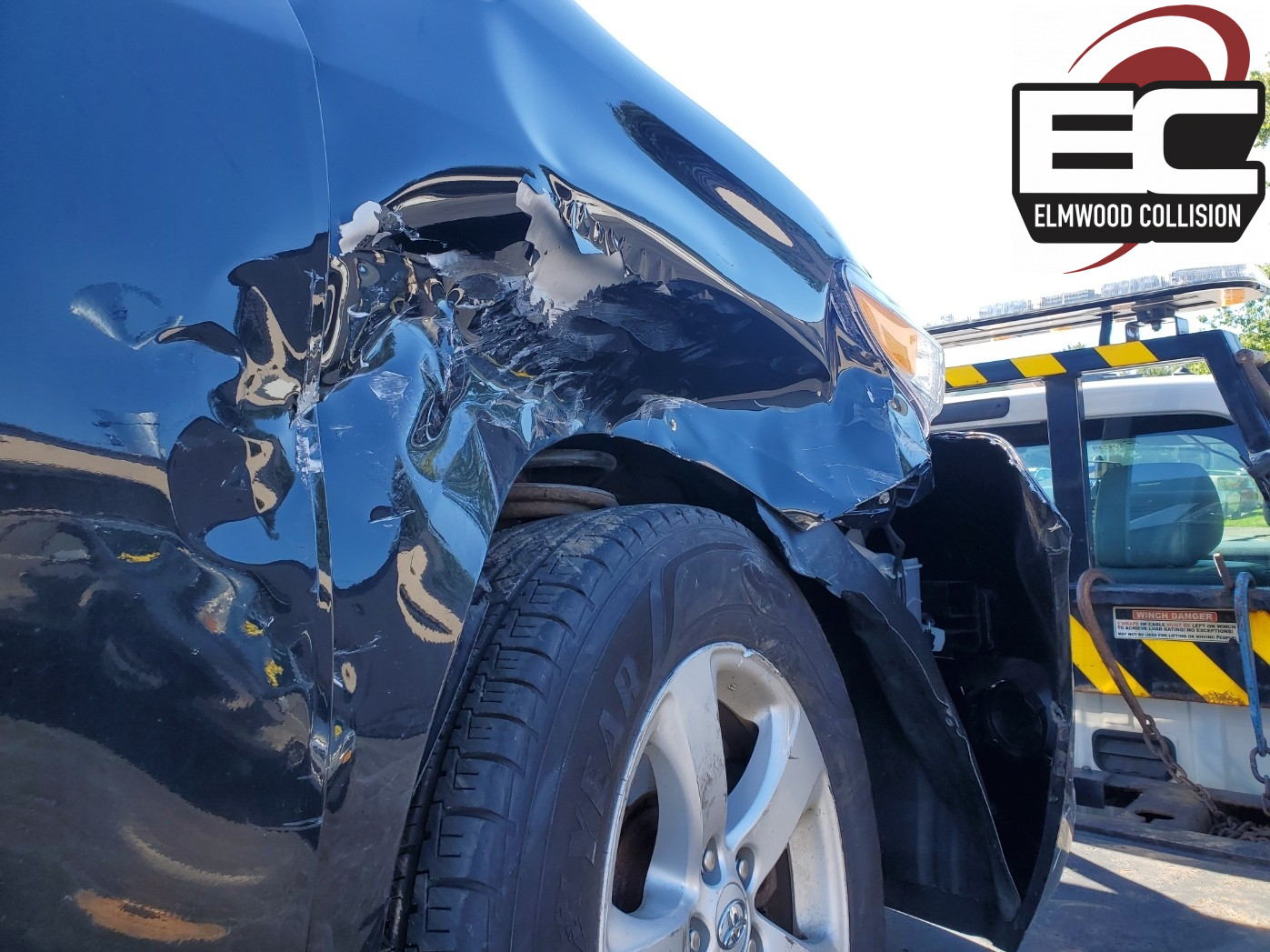 wrecked car on tow truck at elmwood collision for insurance estimate