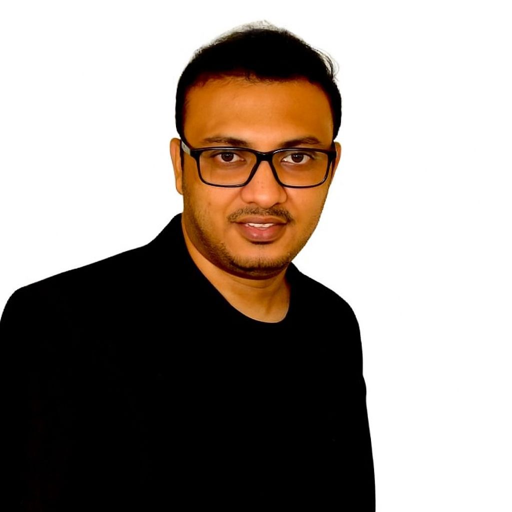 Una persona con gafas y chaqueta negra posa sobre un fondo blanco liso.