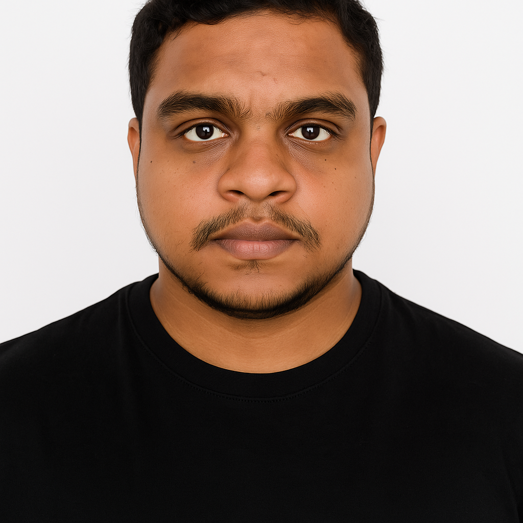 Primer plano de una persona con cabello oscuro y bigote, que lleva una camiseta negra de cuello redondo, sobre un fondo blanco liso.