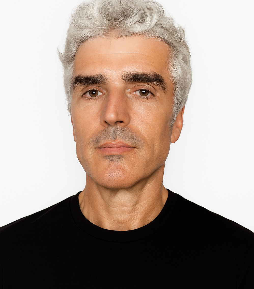 Primer plano de una persona con cabello ondulado y canoso, que viste una camisa negra sobre un fondo blanco liso.