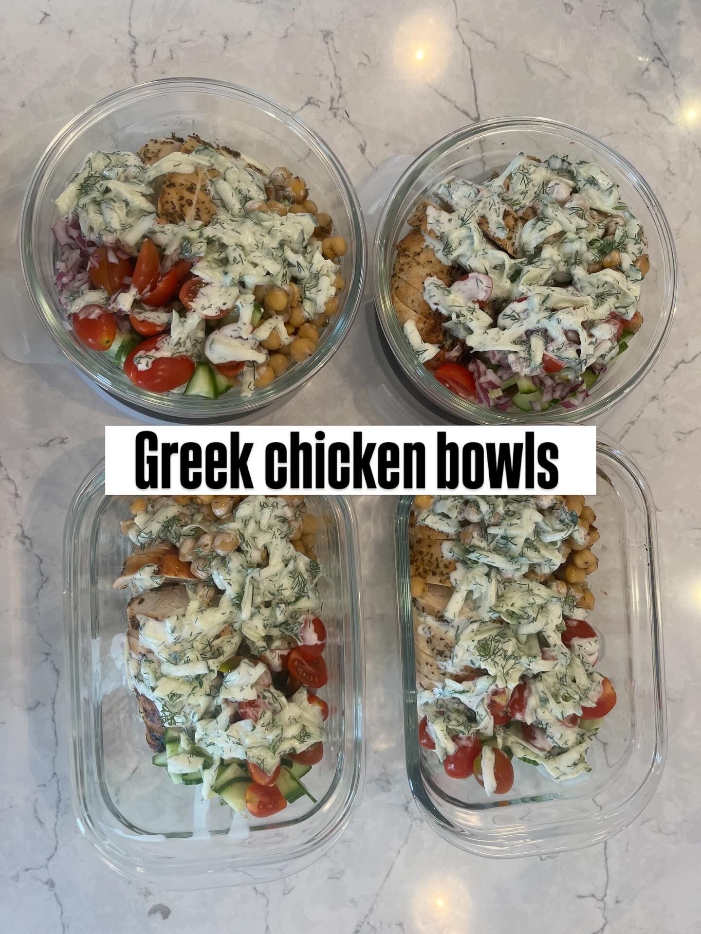 Four meal prep containers of Greek chicken bowls topped with herbs and tomatoes