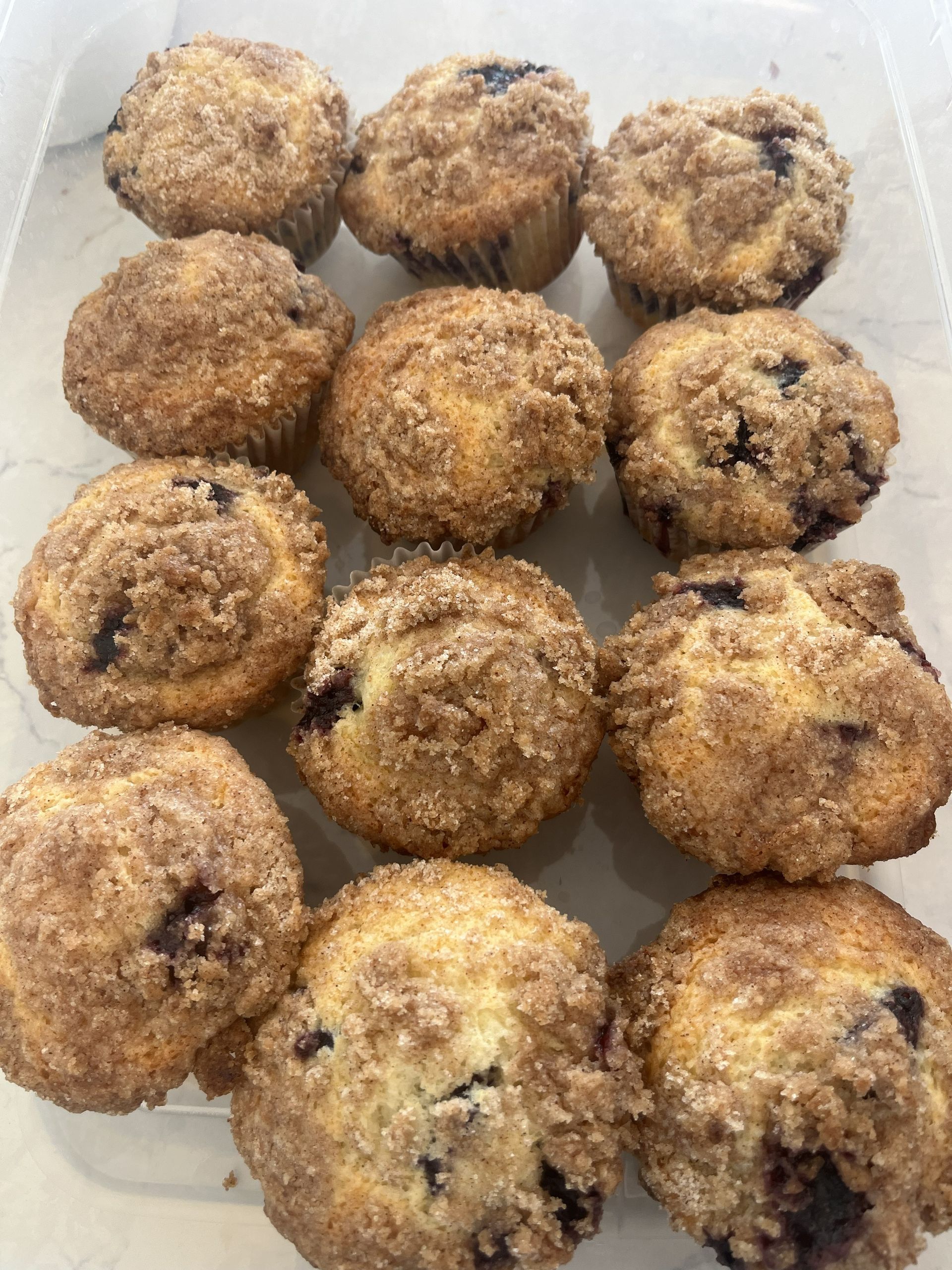 A tray of golden-brown muffins or crumb-topped pastries arranged in a close-up view.