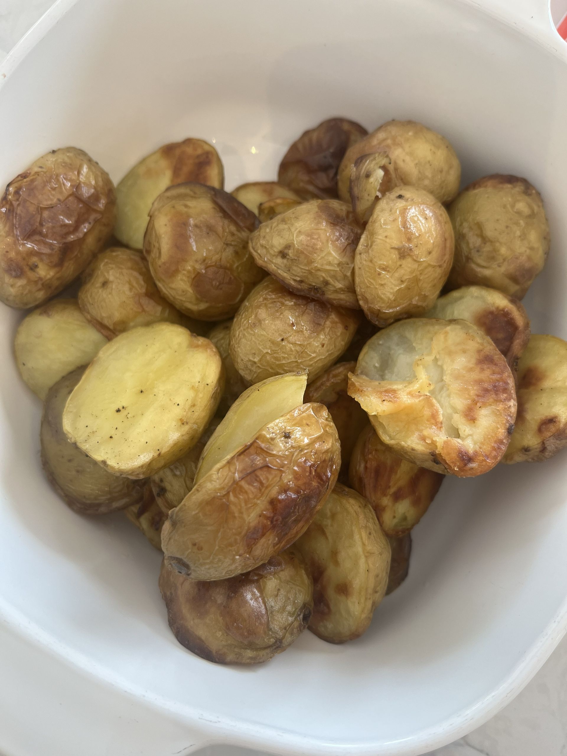 Bowl of roasted baby potatoes, golden brown with a few cut open to show the pale interior