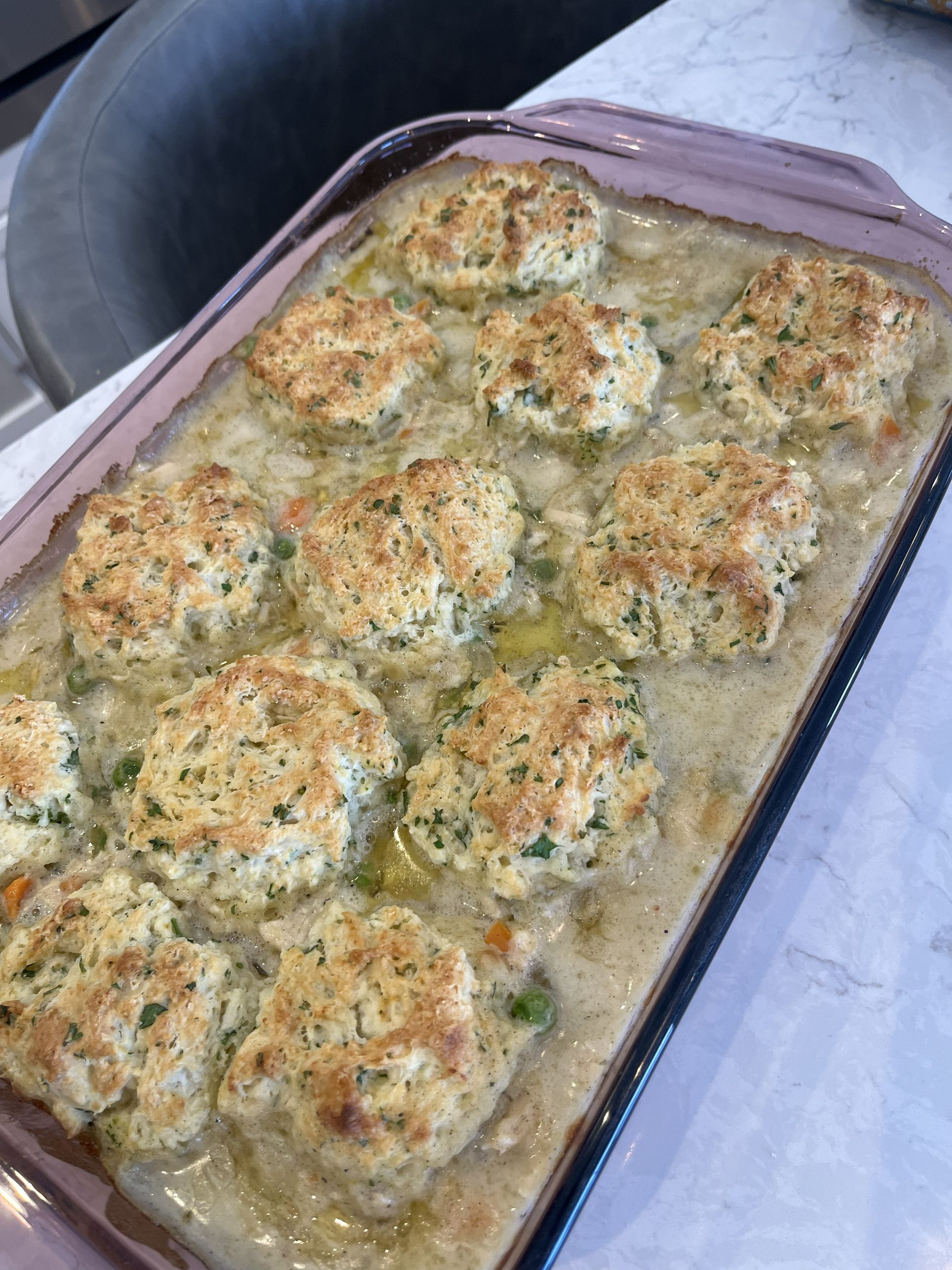 Baked casserole topped with browned biscuits in a glass baking dish