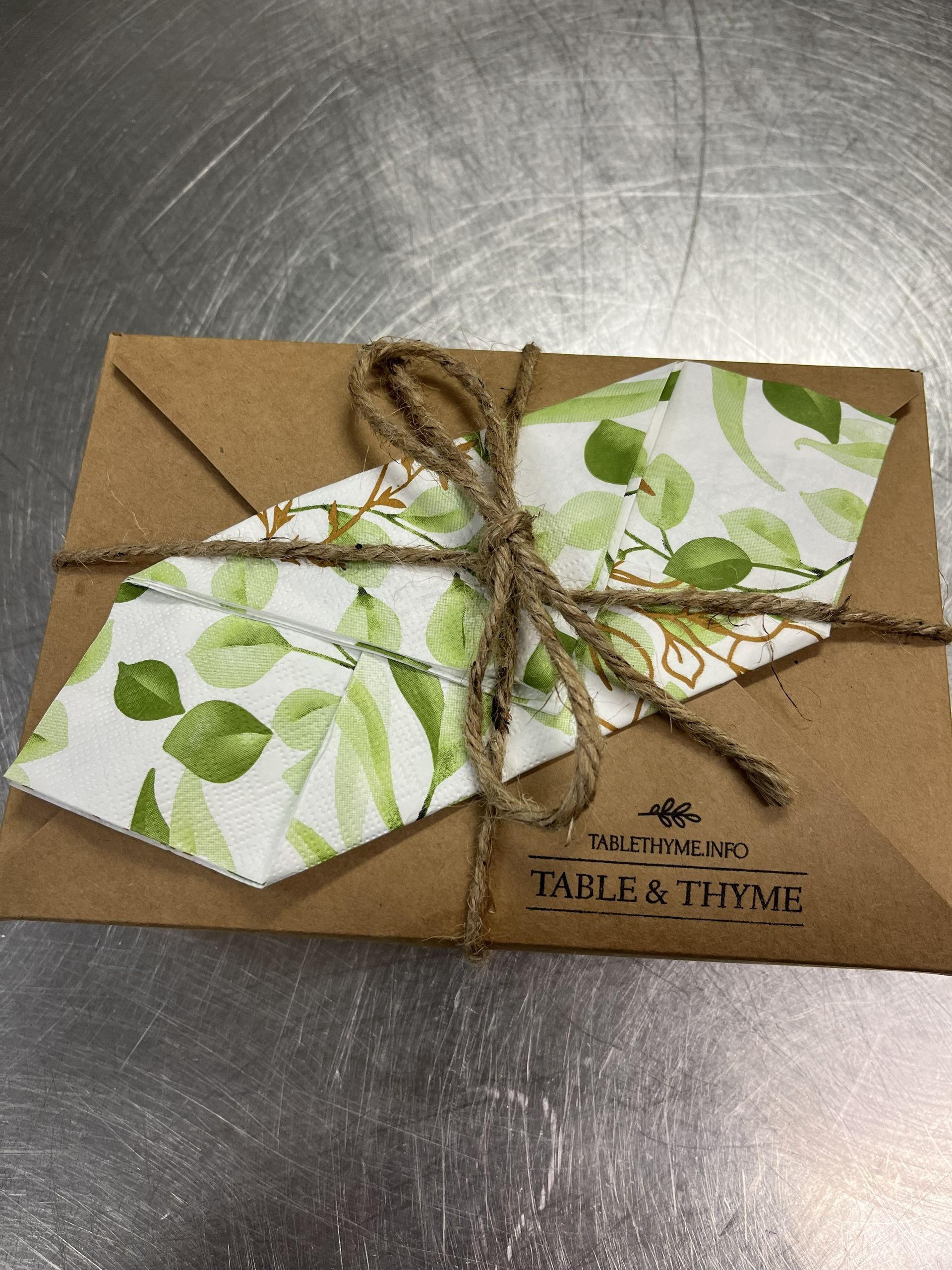 Gift card holder on brown kraft paper with green leaf pattern and twine bow.