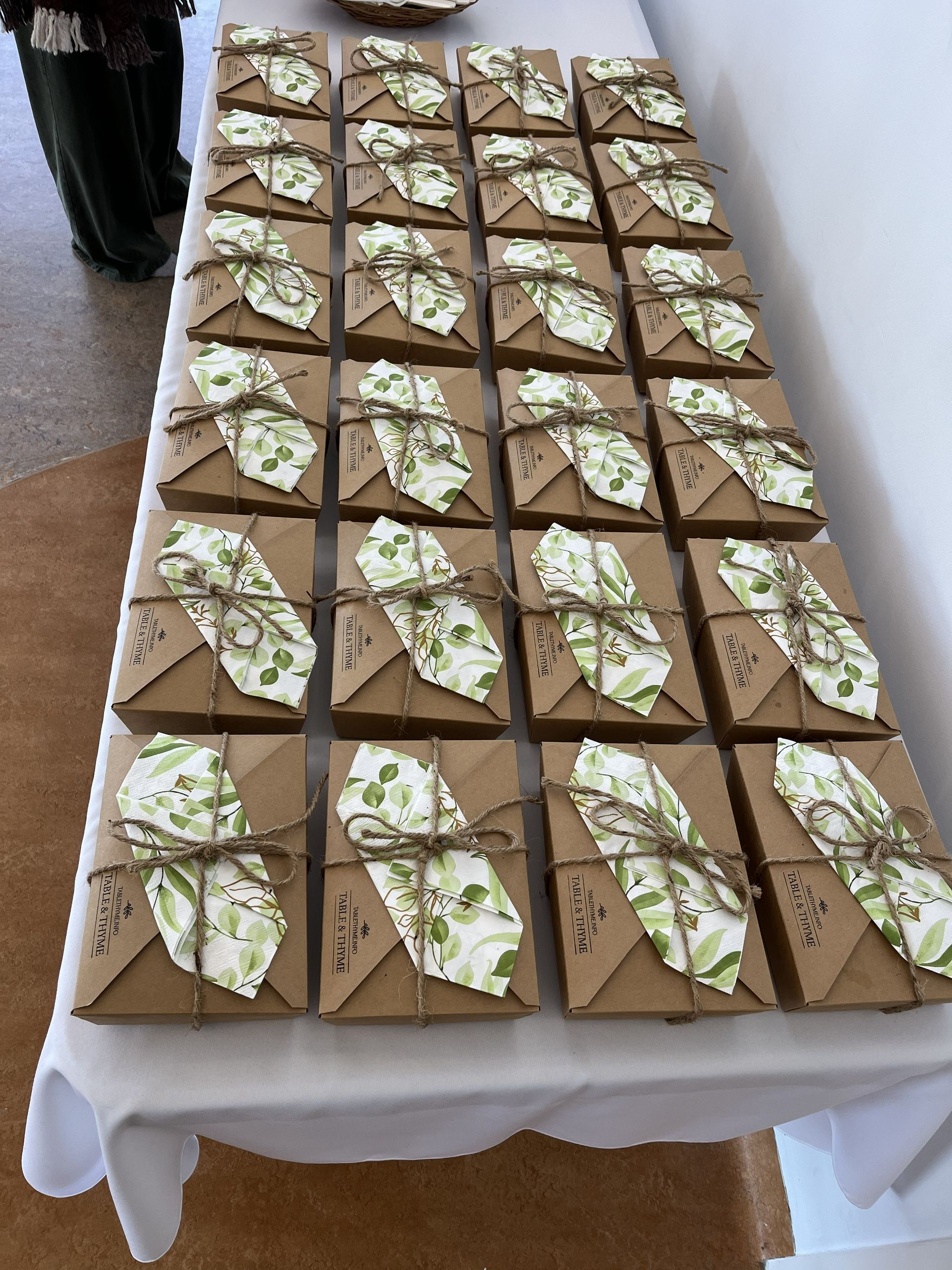 Tray of small square dessert pieces arranged in rows on a table, drizzled with white icing and green garnish