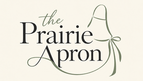 Logo reading “The Prairie Apron” in black and sage green script on a cream background.
