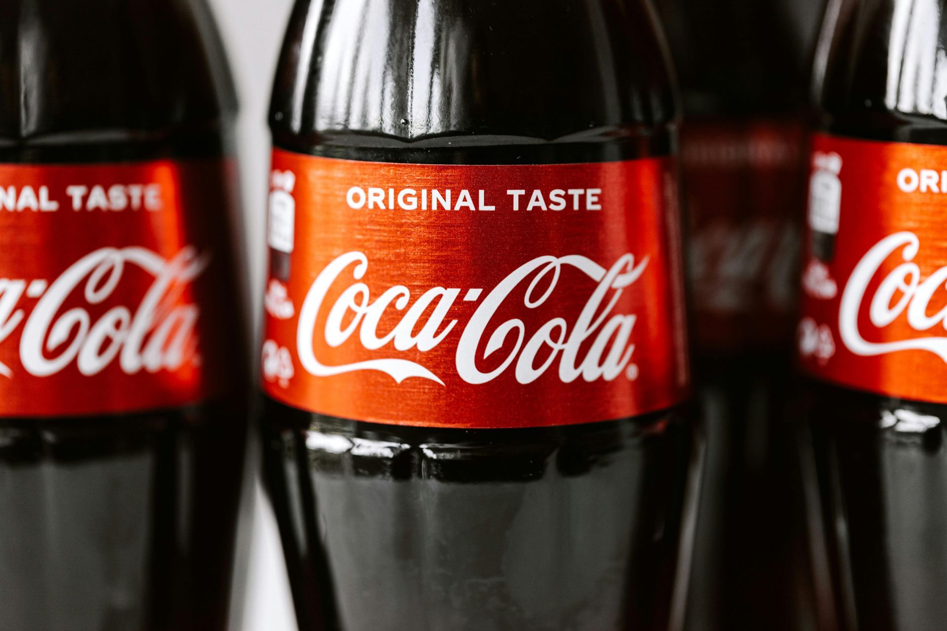 Close-up view of several Coca-Cola bottles with red labels and the classic white logo on a dark background.