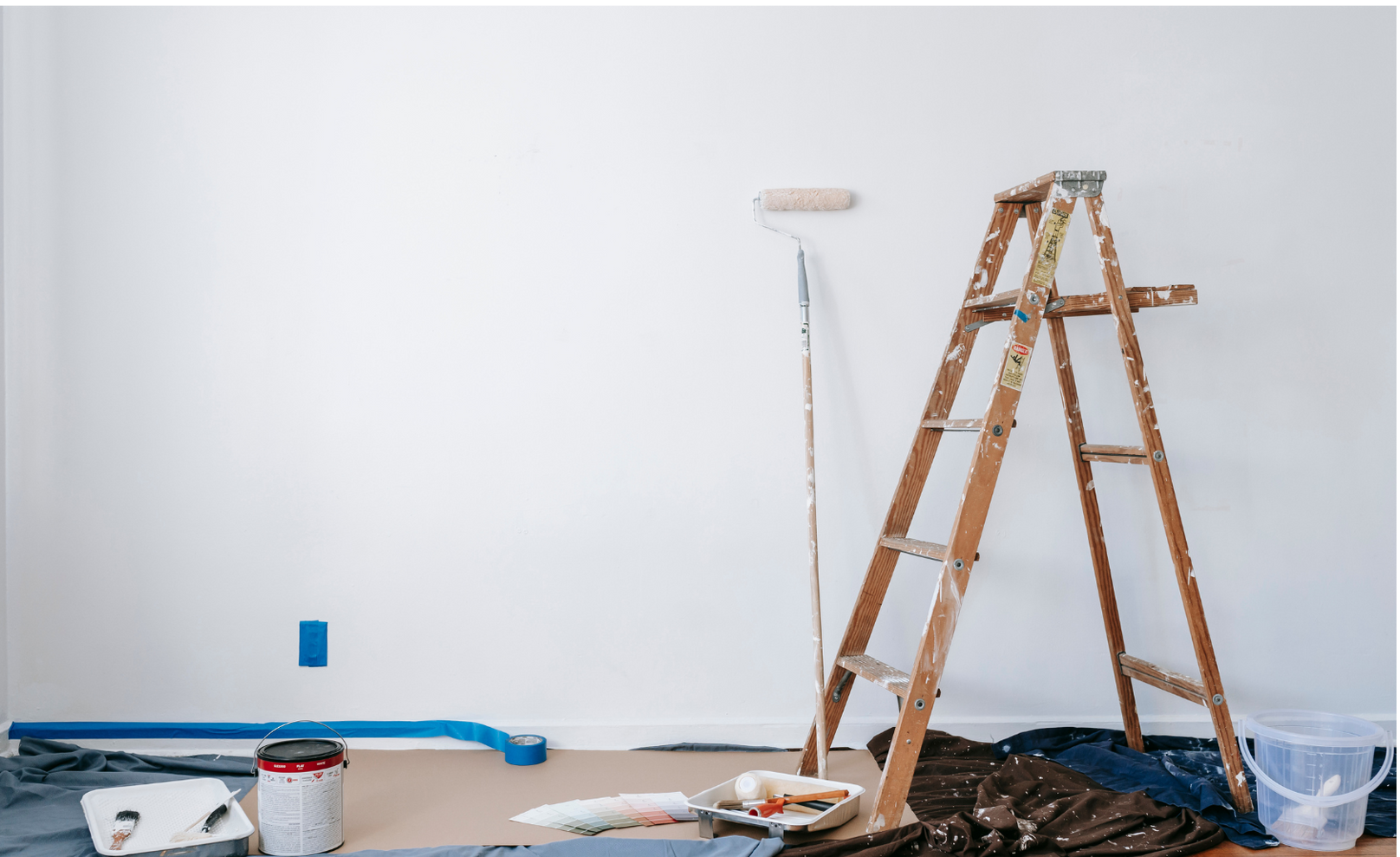 A room is being painted with a ladder and paint roller.