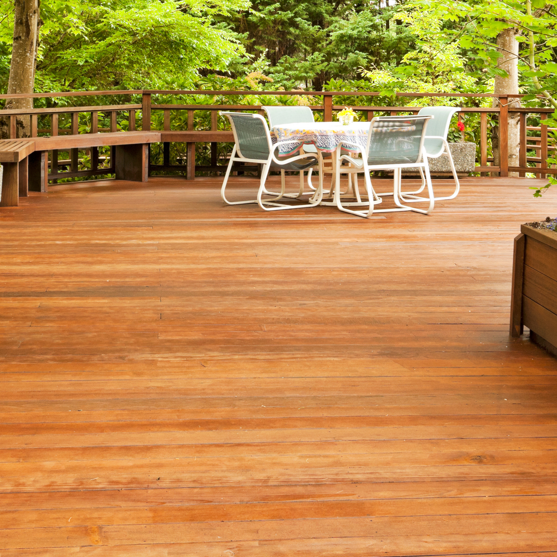 Wooden deck with white patio table and chairs overlooking lush greenery