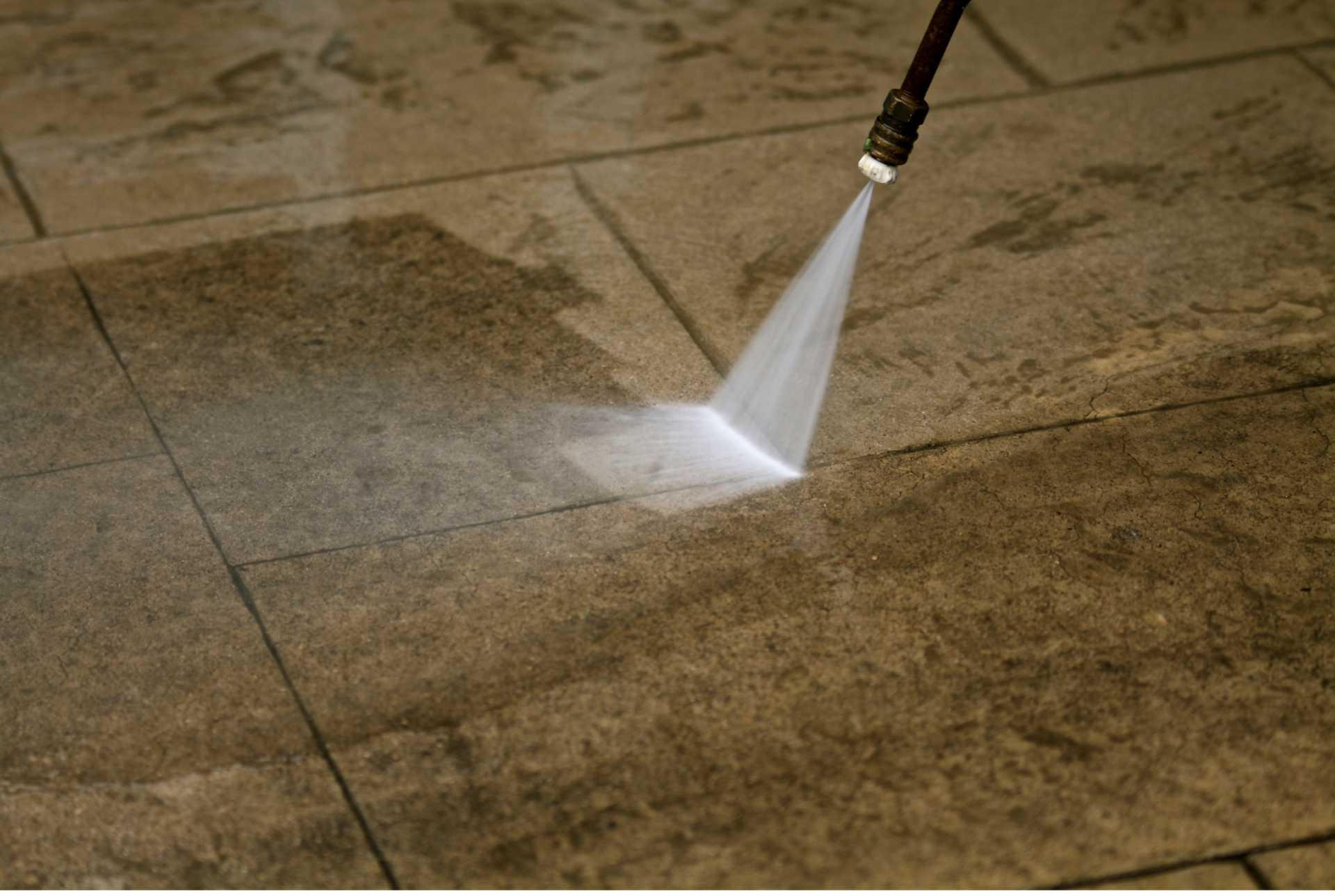 A person is using a high pressure washer to clean a tile floor.