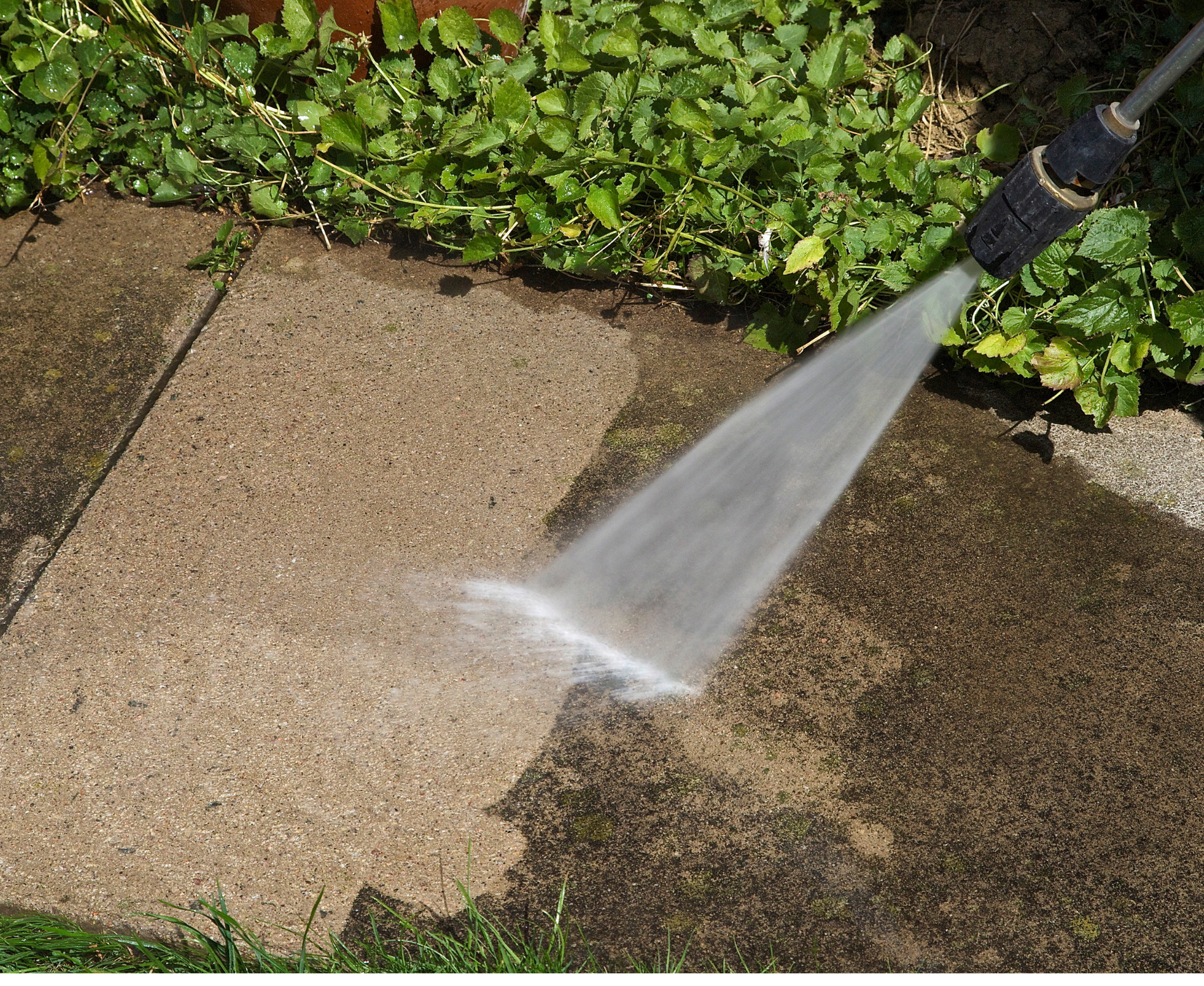 A person is using a high pressure washer to clean a sidewalk
