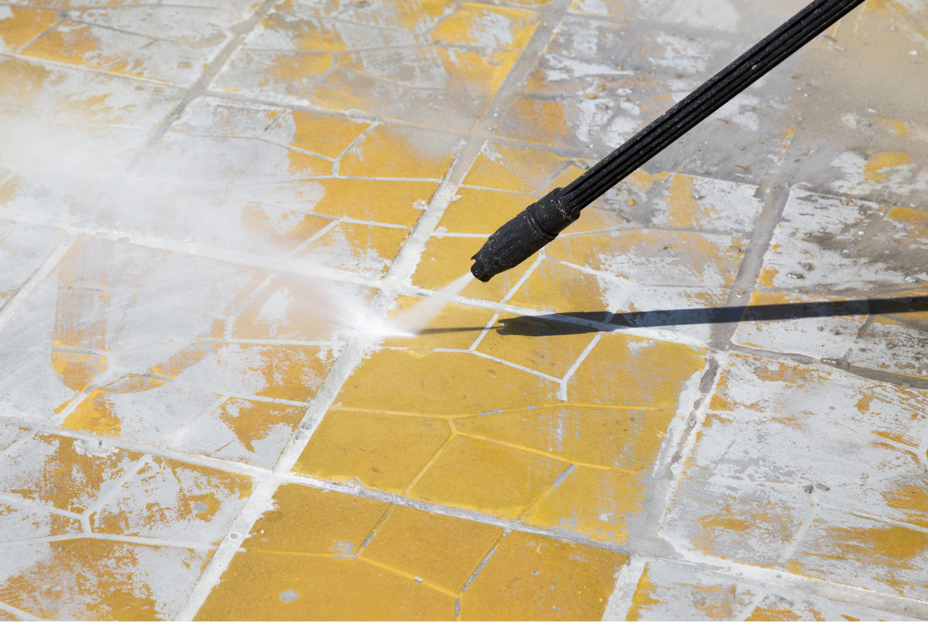 A person is using a high pressure washer to clean a tile floor.