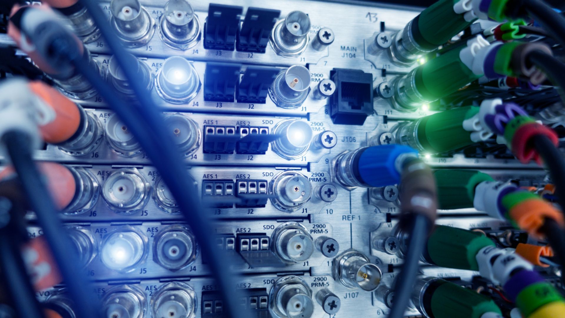 Close-up of a server panel with various connected cables in multiple colors and glowing lights. Close-up of a server panel with various connected cables in multiple colors and glowing lights.