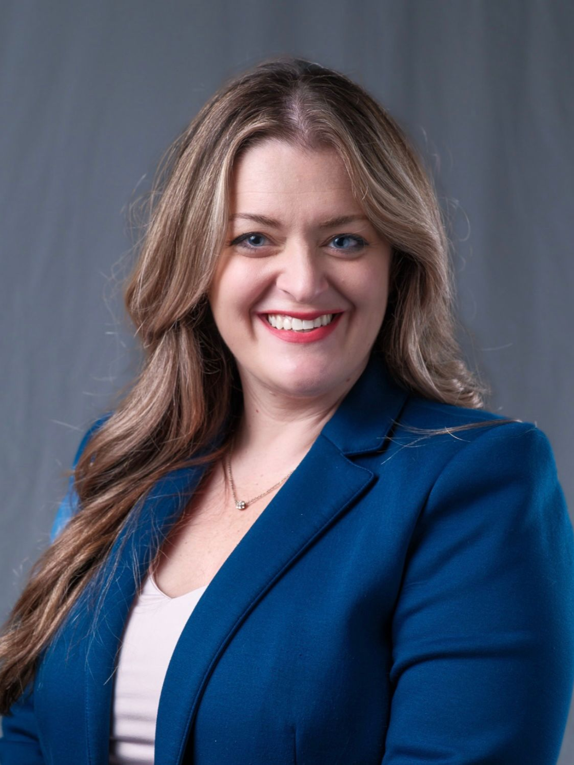 Jessica Natal headshot. A woman smiling, wearing a white shirt and dark blue blazer.