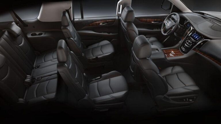 Interior view of a luxury SUV with black leather seats and wood trim; focus on the seating arrangement.
