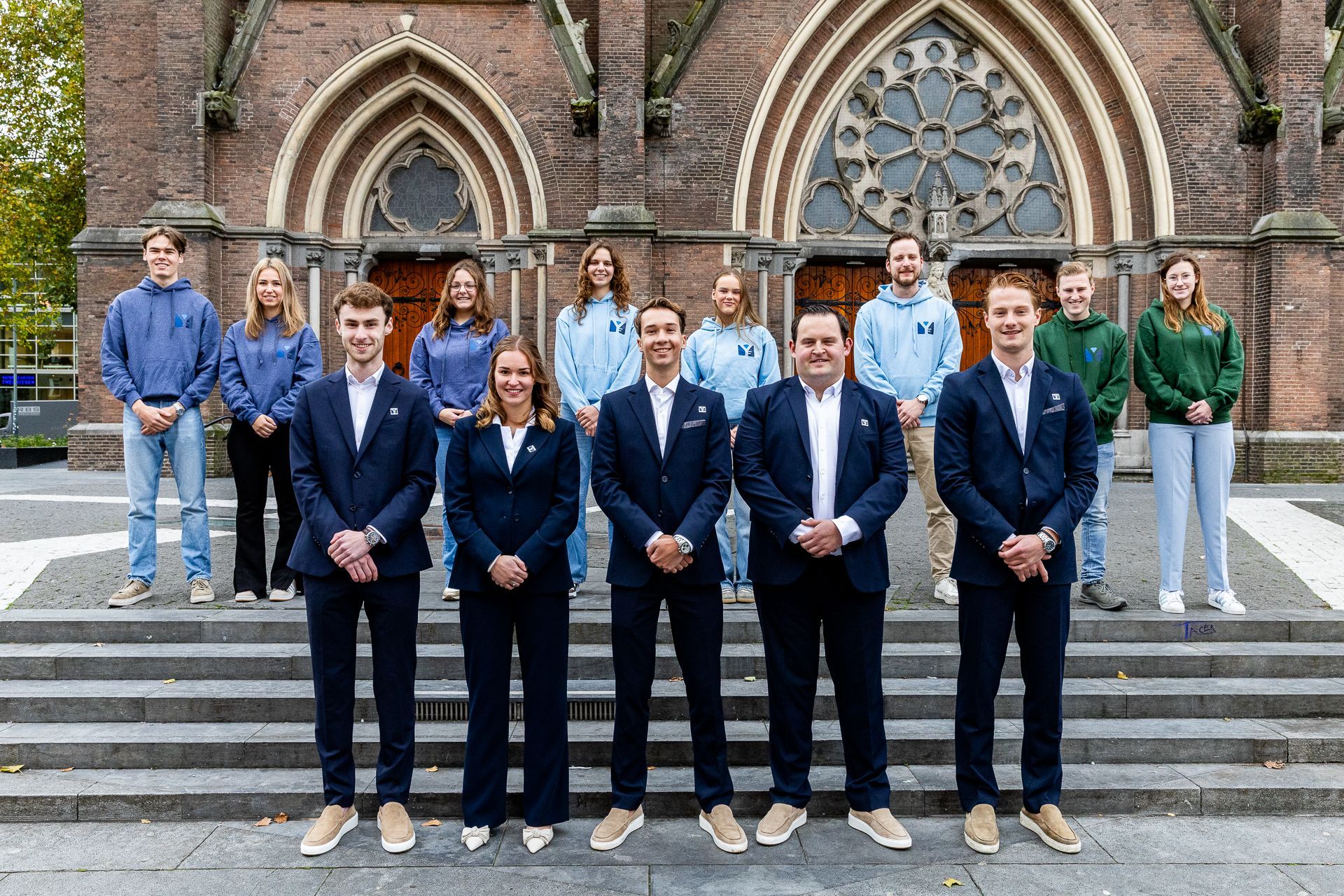 Een groep mensen in zakelijke kleding poseert op de trappen voor een gebouw.