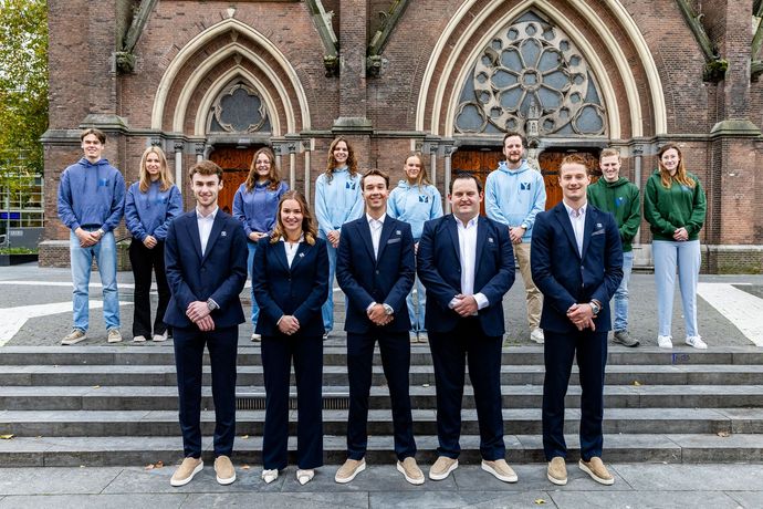 Een groep mensen in zakelijke kleding poseert op de trappen voor een gebouw.
