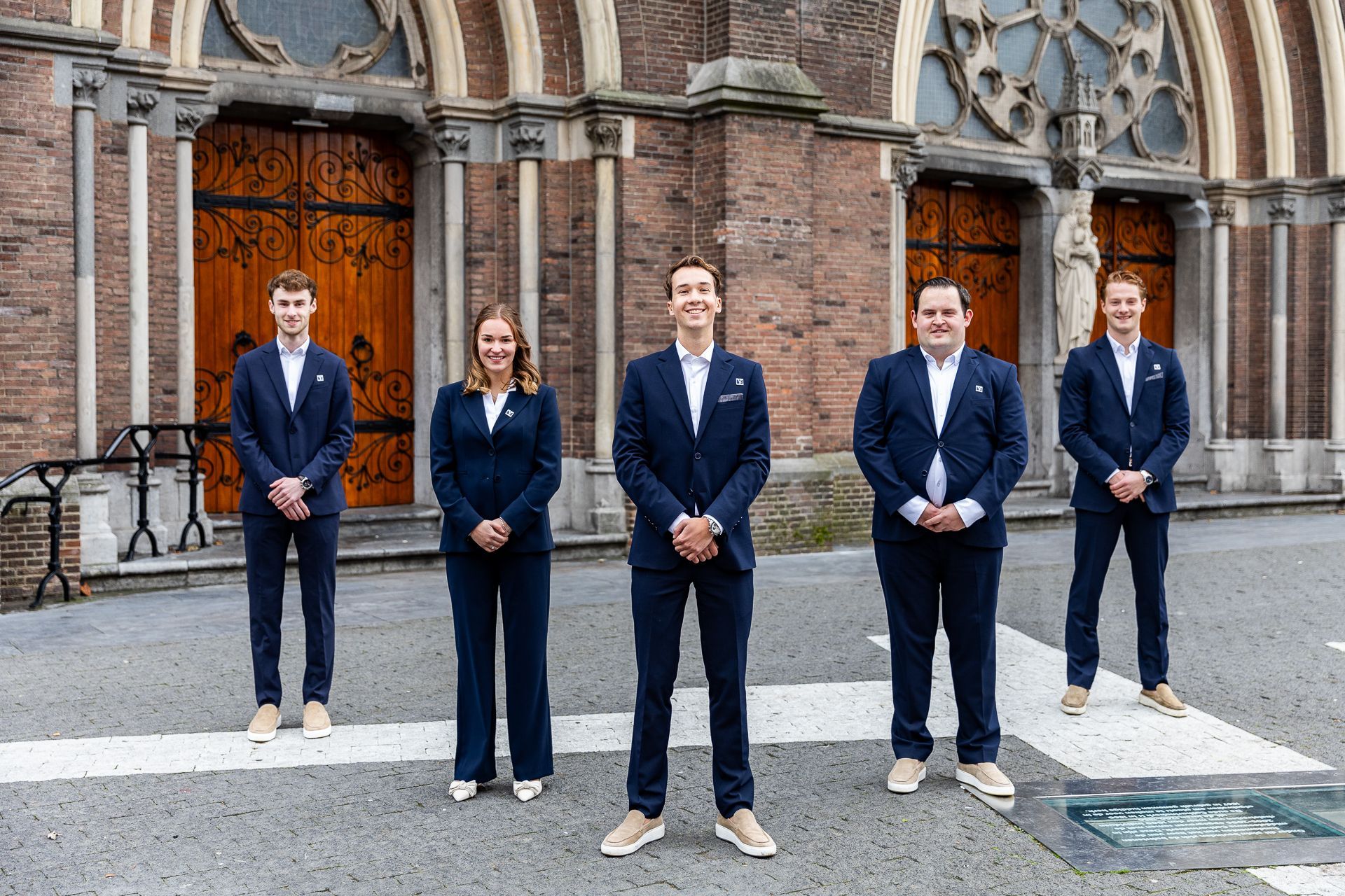 Een groep mensen in zakelijke kleding poseert op de trappen voor een gebouw.