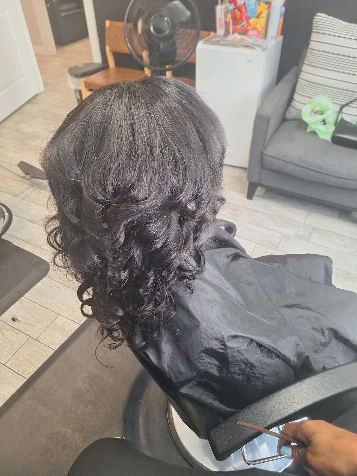A woman is sitting in a chair with her hair cut in a salon.