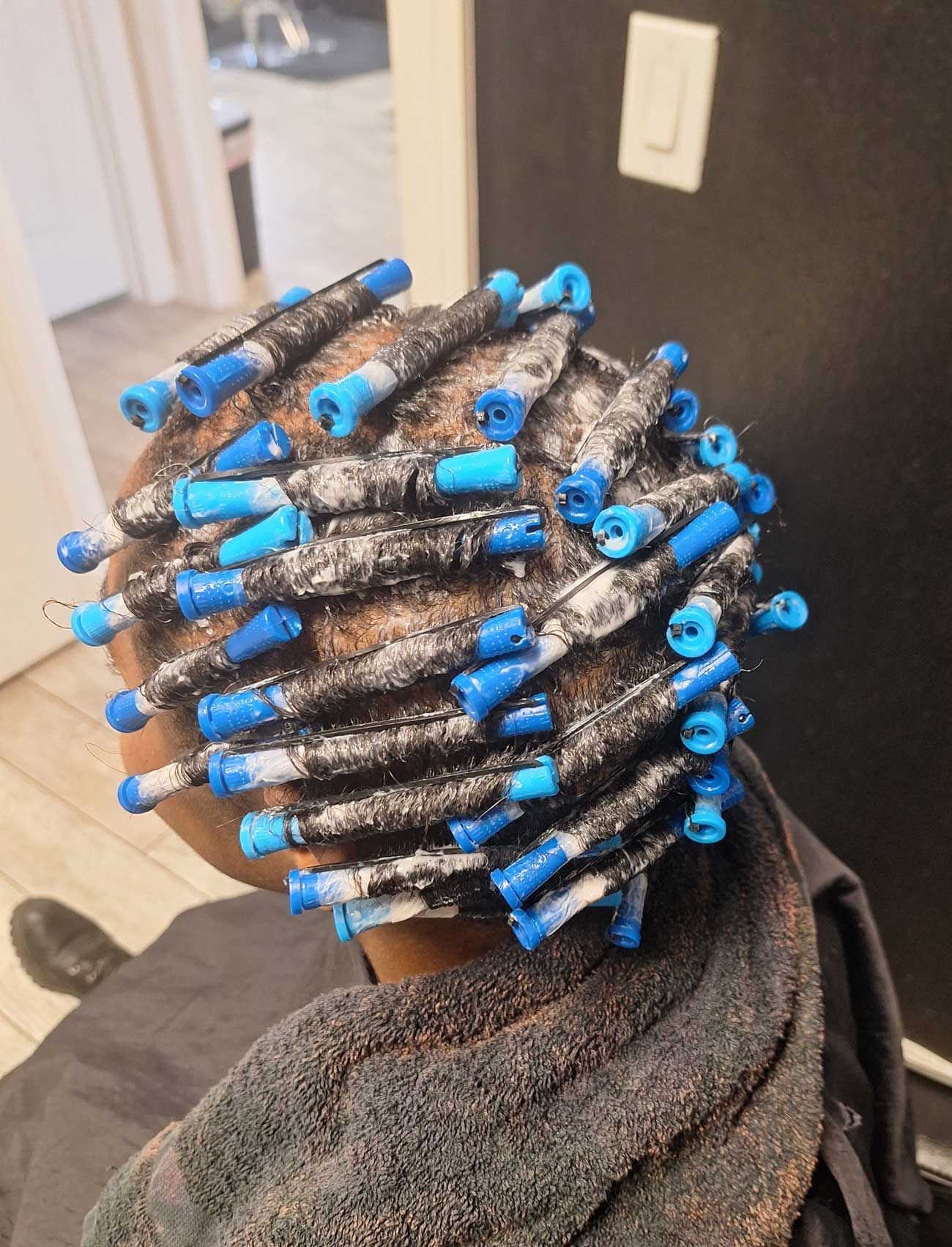 A woman with blue curlers in her hair is sitting in a chair.