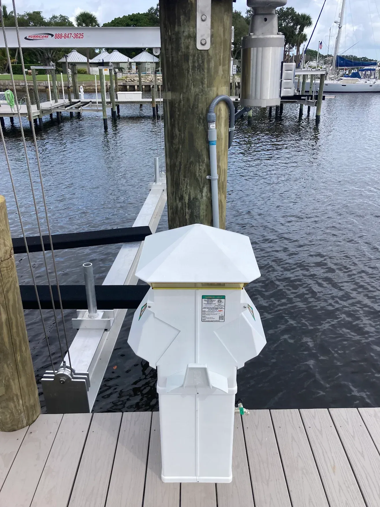 A white pole is sitting on a dock next to a body of water.