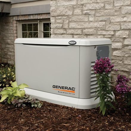 A generator is sitting in front of a brick wall