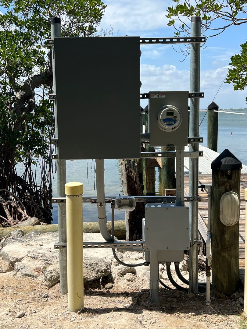 A large electrical box is sitting next to a body of water.