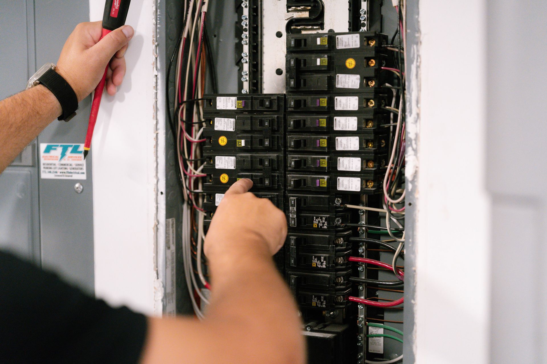 A man is working on an electrical panel with a screwdriver.