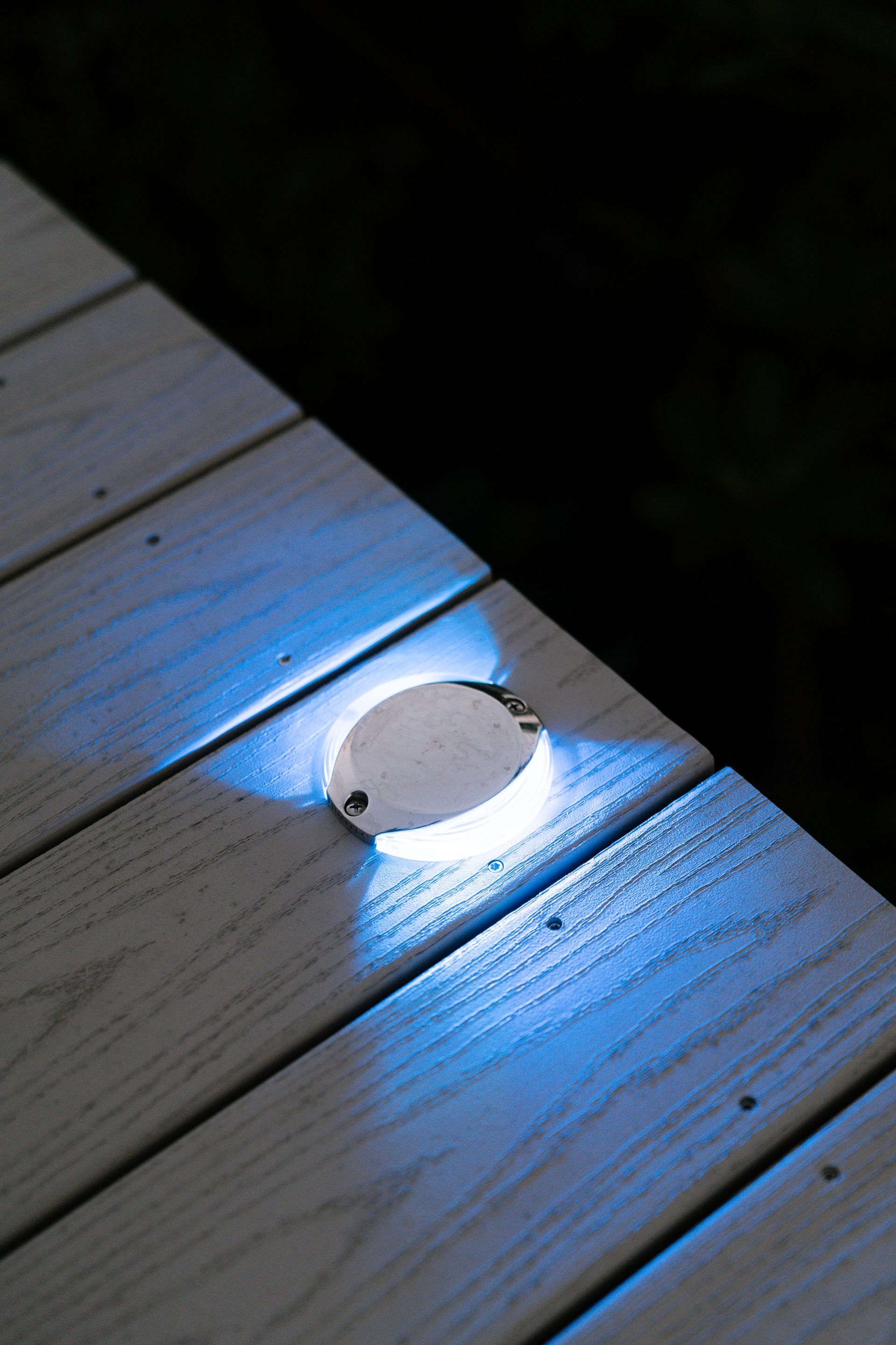 A light is shining on a wooden deck at night.