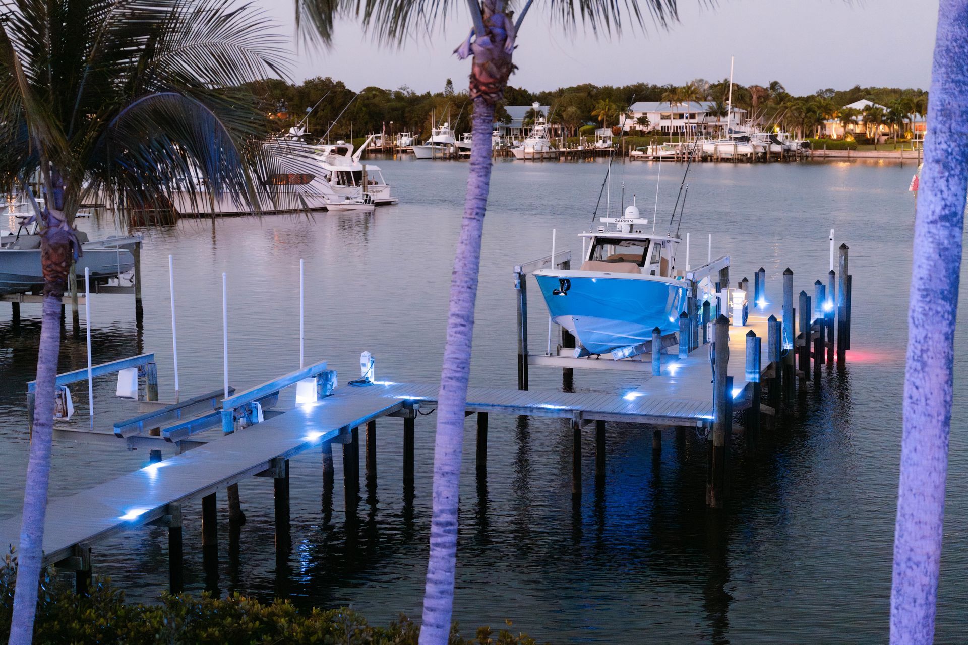 A boat is docked at a dock in the water surrounded by palm trees.