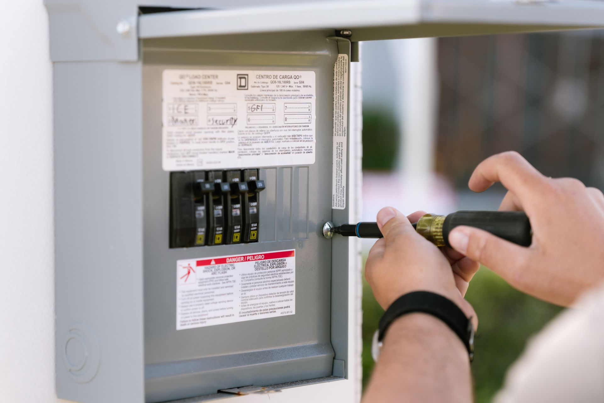 A man is fixing an electrical box with a screwdriver.