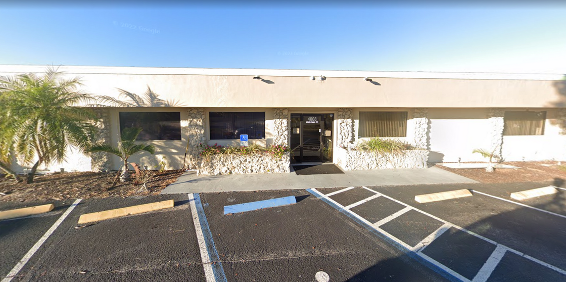 A large white building with a handicapped parking spot in front of it.