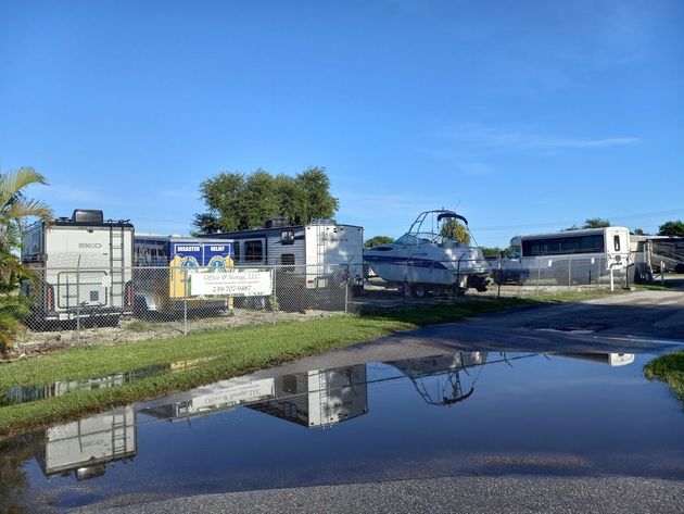 A row of rvs are parked in a parking lot next to a puddle of water.