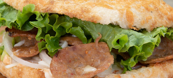 Primo piano di un panino con lattuga, affettati e pane tostato.