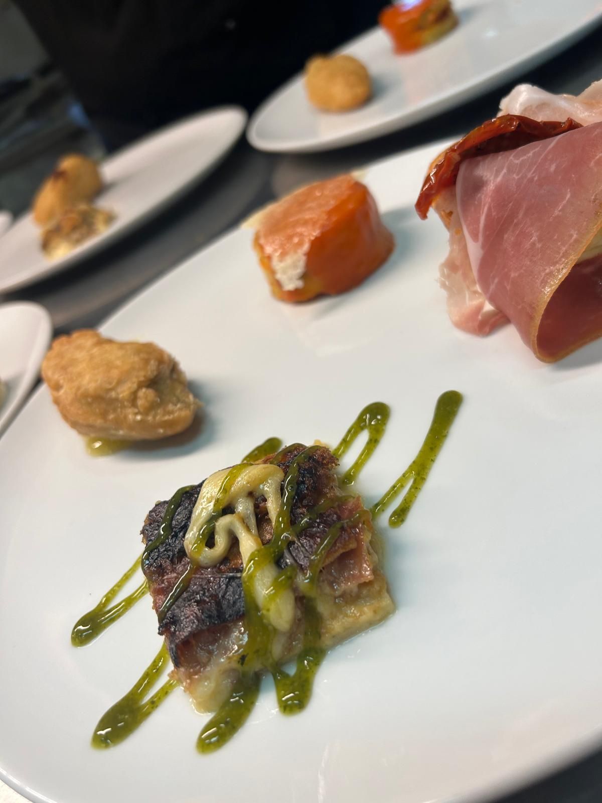 Piatto degustazione gourmet con antipasti in formato mini, tra cui sashimi, serviti su piatti bianchi a un tavolo di ristorante.