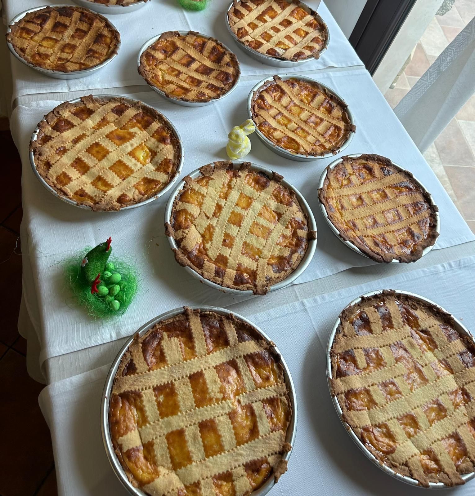 Diverse torte con la copertura a griglia si stanno raffreddando su un tavolo bianco vicino a una finestra.