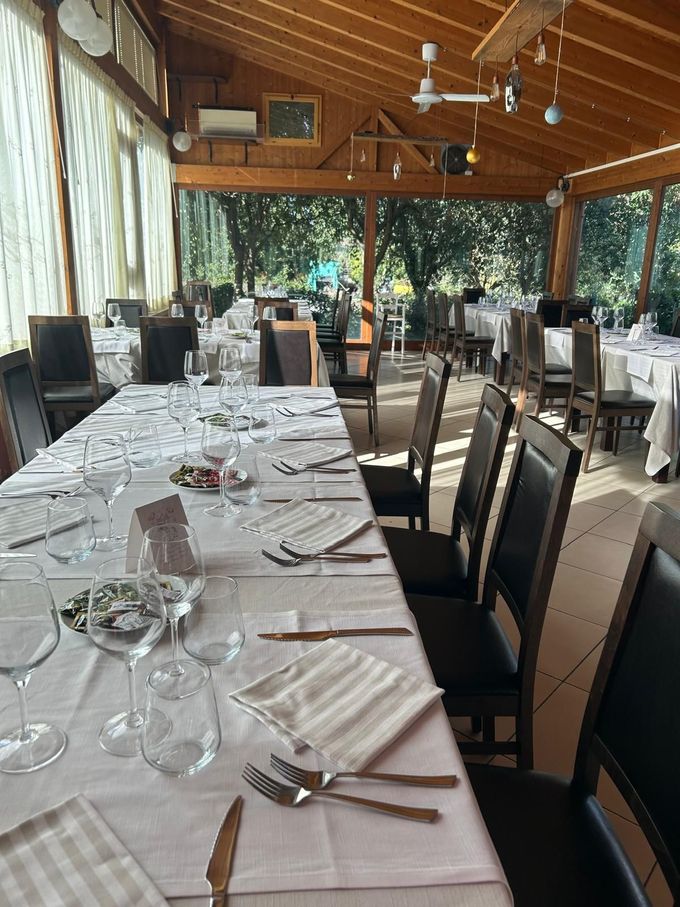Tavolo apparecchiato in un ristorante all'aperto coperto con tovaglie bianche e soffitto in legno.