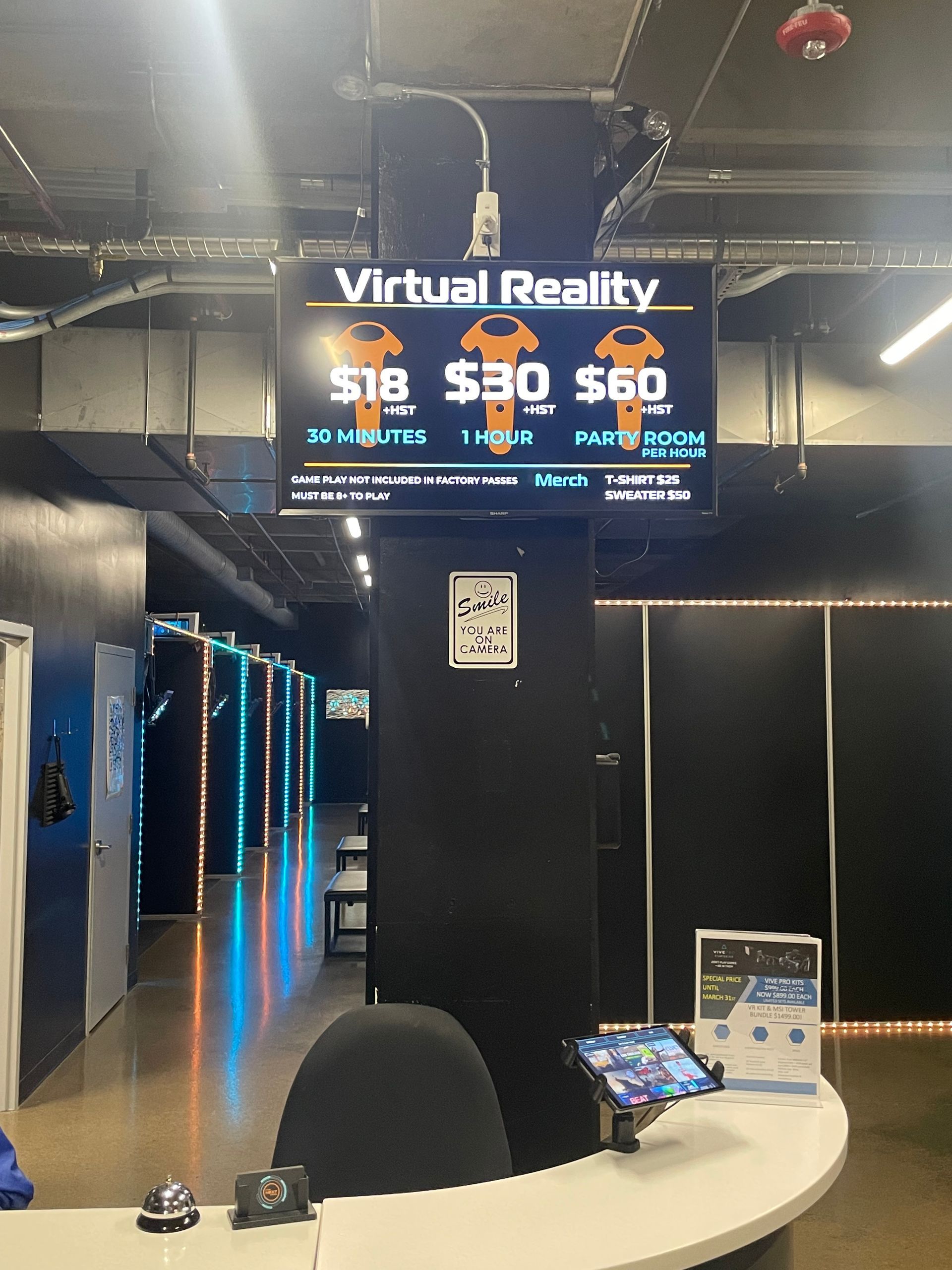 Virtual reality arcade lobby with glowing blue-lit VR stations and a service counter